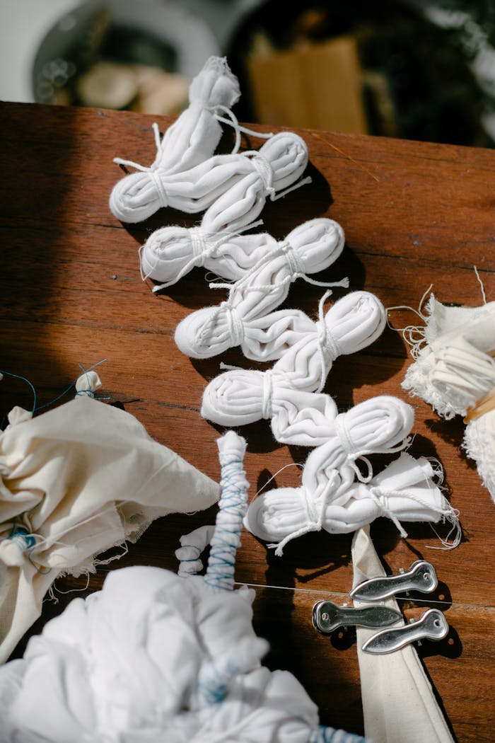 High angle of pleated cotton fabrics tied with threads on desk with pins for tie dye on sunny day